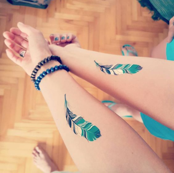 best friends matching feather tattoos on forearm