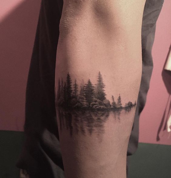 green trees forest reflection tattoo on arm