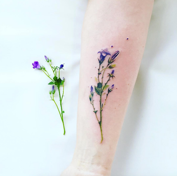 realistic wildflower tattoo on forearm