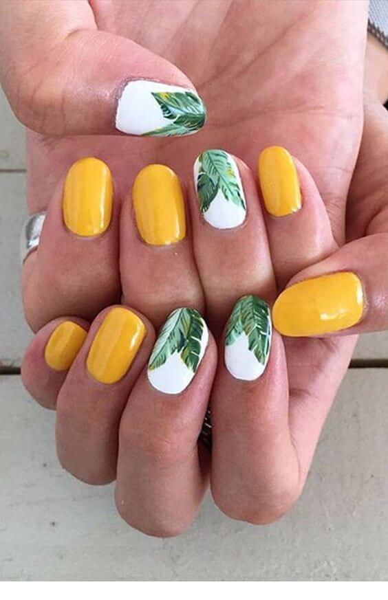yellow nails with green leaves on white nail polish