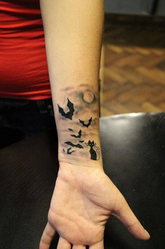 spooky cat with bats flying halloween tattoo idea